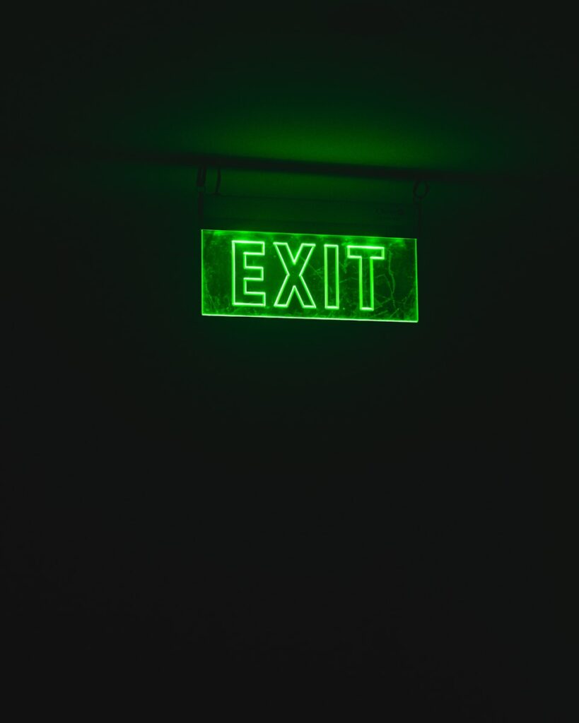 a green exit sign lit up in the dark